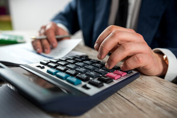 business man work with calculator at annual finance documents at office