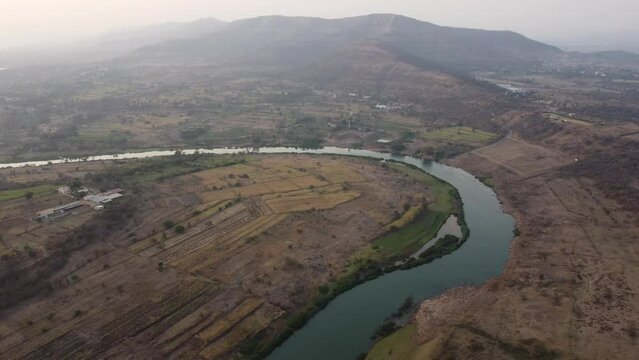Drone 4k Footage of a River Bend in Country Side with Hills, Farms, and Fields, Nature on a Hazy Afternoon. Pune, Bhor, India Villages