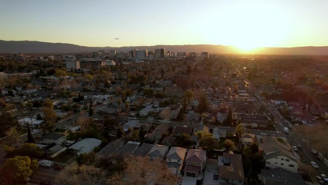 San Jose Aerial push in at sunset with plane landing over city