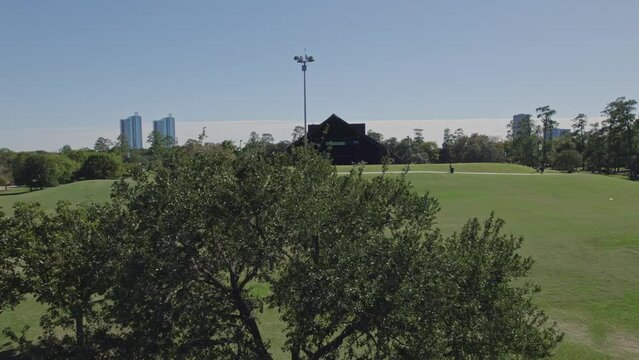 Aerial - Reveal of Hermann Park over a tree on a sunny day in Houston, TX