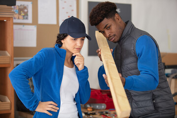male carpenter with female apprentice looking at wood