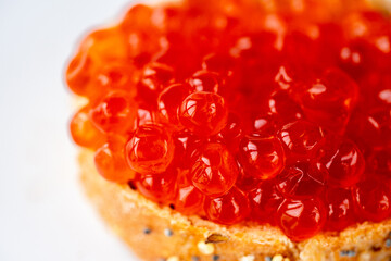 Red caviar sandwich. Red salmon caviar glows on a white background. Luxurious gourmet food. Raw seafood. Macro fish caviar.\nTexture of red caviar. Salmon caviar is grainy. Juicy fresh red caviar  - obrazy, fototapety, plakaty