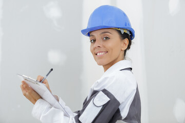 smiling woman builder holding clipboard with pen