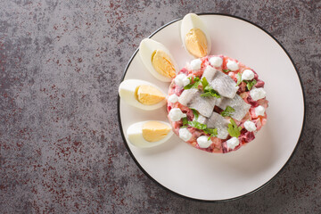Herring salad with beets, apple, potatoes and onions close-up in a plate on the table. Horizontal top view from above