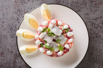 Delicious vegetable salad with herring, beetroot, apple, potato and onion close-up in a plate on...