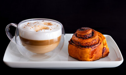 cappuccino with many layers of coffee, milk and foam and snails with cocoa on black background....