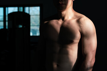 Fototapeta na wymiar Sexy body of muscular young Asian man in gym. Concept of health care, exercise fitness, Strong muscle mass, body enhancement, fat reduction for men's health supplement product presentation.