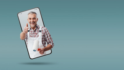 Confident painter and decorator  in a smartphone videocall and smiling, online  service concept © stokkete