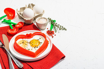 Heart-shaped fried egg served with toasted bread. Romantic art food idea for Valentine's breakfast