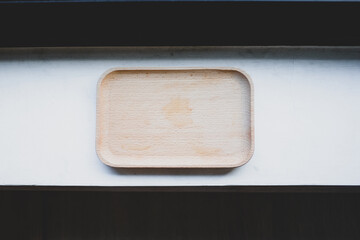 Wood tray or wood coaster on white cement in the restaurant.
