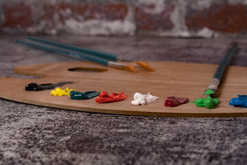 wooden palette with colored oil paint and brushes