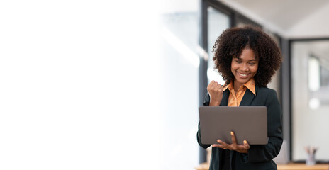 Happy businesswoman feeling excited with hands up while looking at laptop computer, receive great news from her boss.