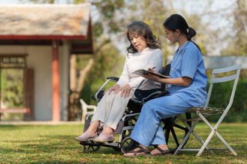 Elderly asian senior woman on wheelchair with nurse. Nursing home hospital garden concept