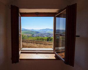 view from the open old wooden window. hills rolling in to the distant mountains. village in the valley