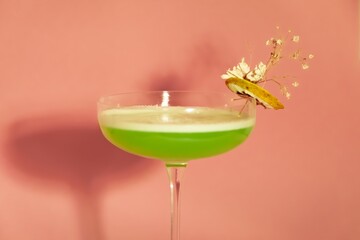 Green cocktail with Gypsophila and dried orange on pink background