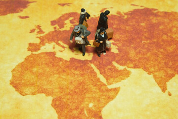 Miniature people toy figure photography. A group of refugee walking above map globe, moving out from their country because of war conflict. Distance traveled concept
