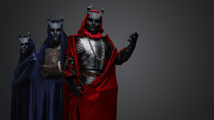 Portrait of dark cultists dressed in robes with hood and black horned masks.