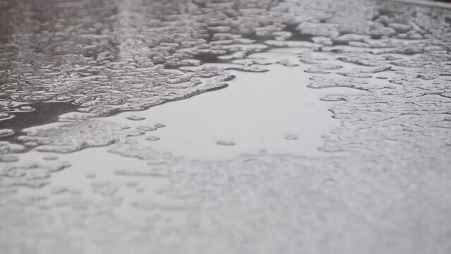 Close up of small dark balcony table with glass surface while bad weather. Puddles and raindrops are visible on the fixed shot. showcases the impact of weather on outdoor surfaces, rain on glass.