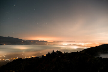 Night view of city lights in the valley. Spectacular cloud waterfall in the sky. The sea of clouds landscape. Dahu Township, Miaoli County, Taiwan