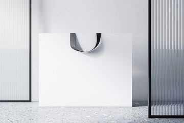 Front view on blank white paper shopping bag with place for your brand name or text on light concrete floor and light wall background, close up. 3D rendering, mockup
