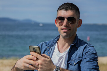 young man with phone and beach background