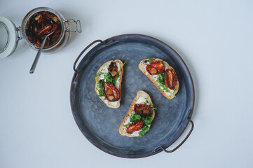 italian traditional bruschetta - bread toast with sun dried tomatoes, cream cheese, olive oil and arugula.