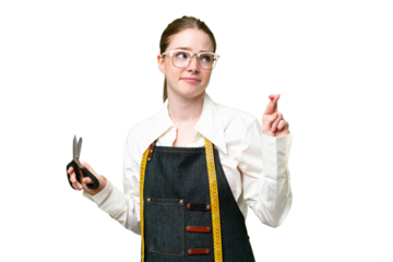 Seamstress woman over isolated chroma key background with fingers crossing and wishing the best