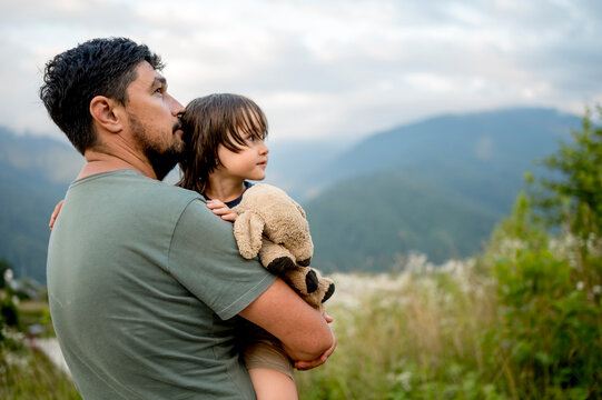 Father carrying son with teddy bear at vacation