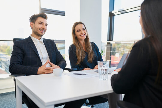 Smiling recruiters taking interview of candidate at desk in office