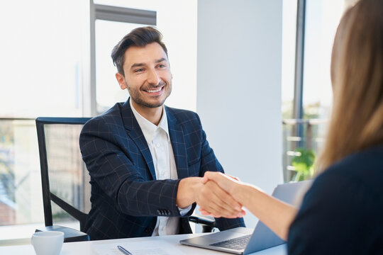 Happy recruiter shaking hand with candidate after interview at office