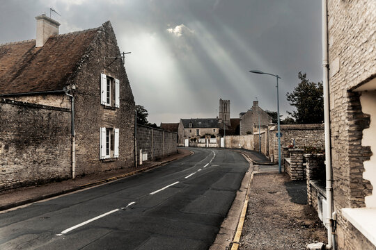 Sunlight streaming through clouds over empty street in old town