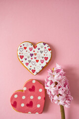 Gingerbread heart. Spring mood. Pastel colors. Delicious gingerbread on a light pink background. Sweet treats for lovers. Heart-shaped honey cake. Pink flower and heart