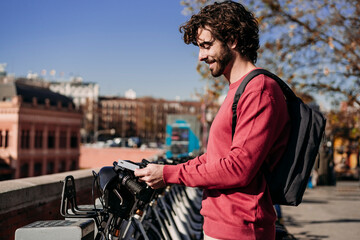 Smiling young man paying with credit card at electric bicycle sharing system