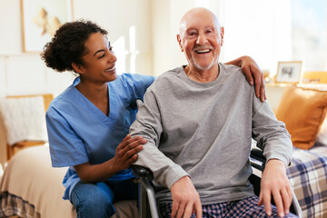 Happy senior man sitting on wheelchair by nurse at home