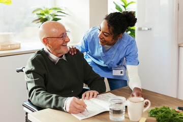 Happy caretaker assisting senior man at home