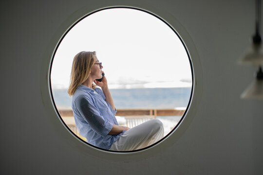 Businesswoman Talking On Smart Phone Seen Through Circle Shaped Window