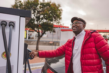 Smiling man charging car at electric vehicle station