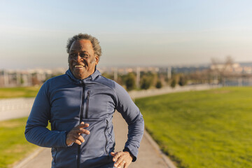 Happy senior man jogging on sunny day