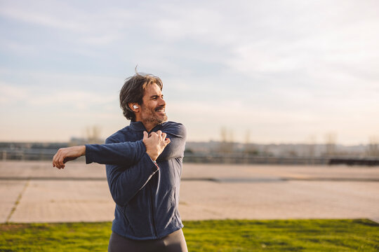 Mature man doing stretching exercise in park - Powered by Adobe