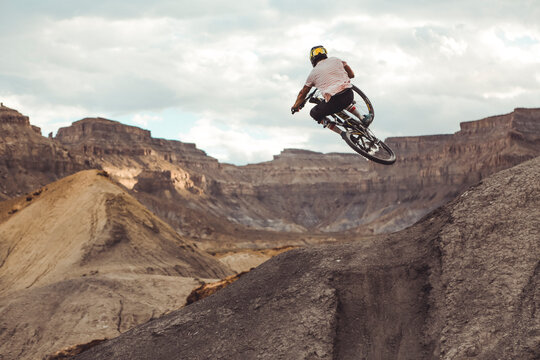 Actionshot of male athlete jumping with MTB in desert