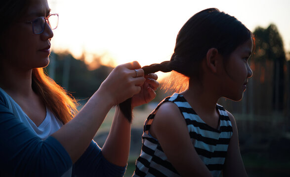 The mother styling her daughter's hair during the sunset