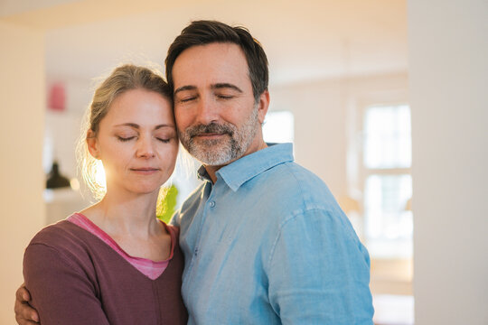 Mature couple with eyes closed at home