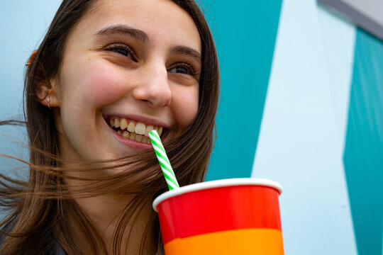 Woman smiling and drinking soda with a straw at a party.