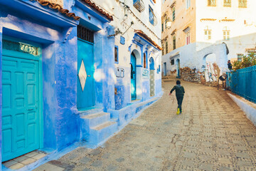 Local boy running in the street of Chefchaouen blue village