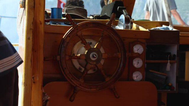 Close-up of the wooden helm and controls on a pleasure craft with tourists. A summer holiday at sea. Wooden steering wheel. The ship sways on the waves