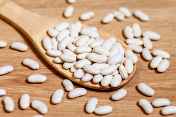 Fototapeta na wymiar White beans in a wooden spoon on a wooden table