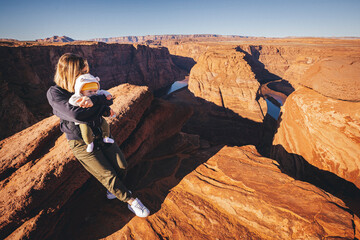 A woman with a child is sitting near Horseshoe Bend, Arizona