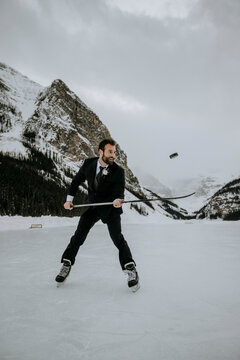 hockey player with suit on juggles puck on frozen lake in mountains