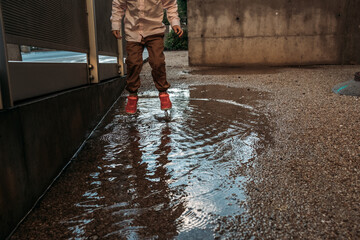 Young child jumping in puddle with pink shoes on