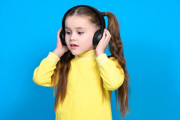 Happy little girl with wireless headphones on a blue background